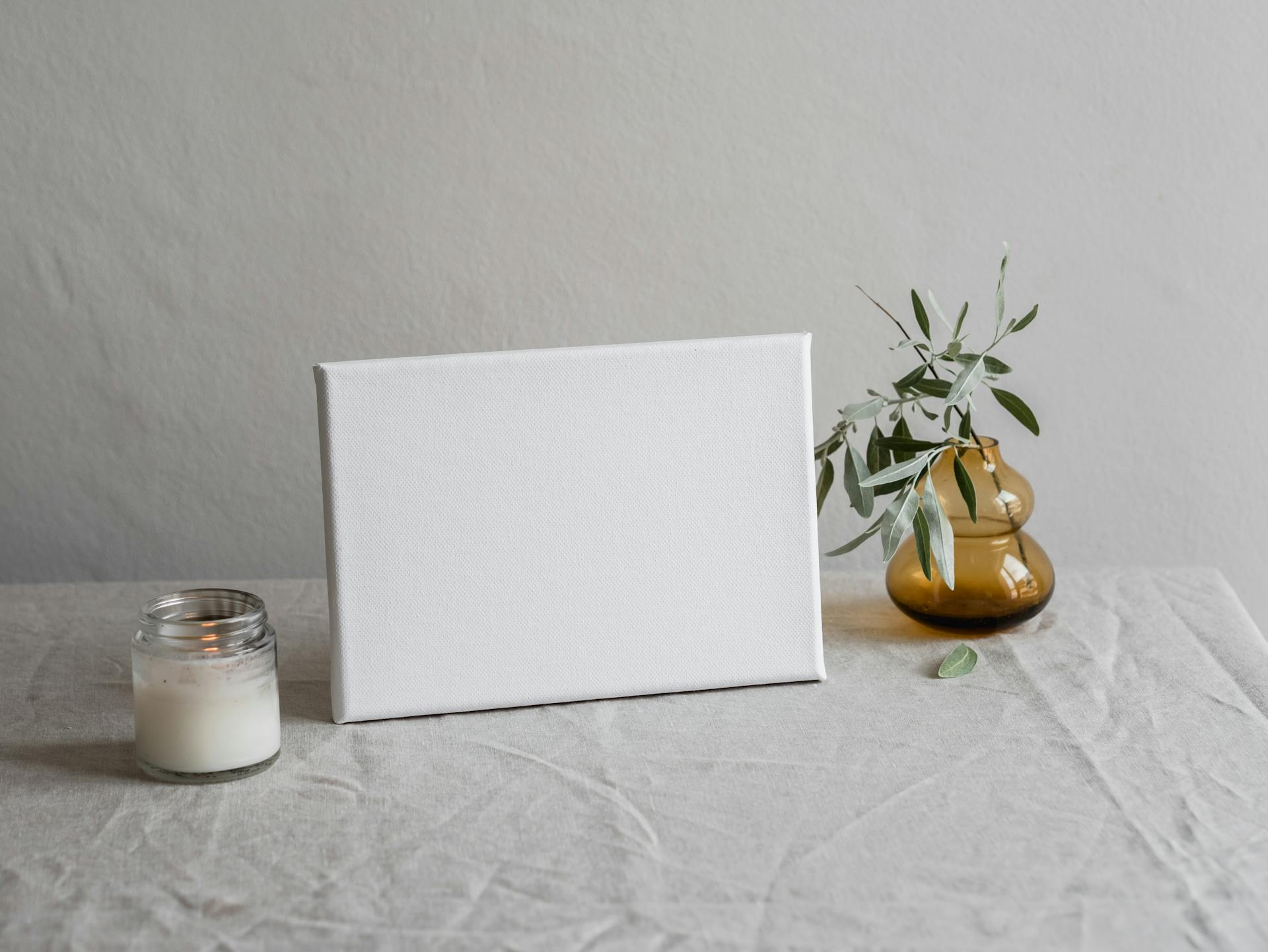 Elegant minimalist canvas mockup on table with candle and vase, perfect for decor inspiration.