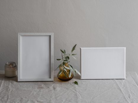 Elegant still life of a table with a photo frame, vase, and candle in a minimalist setting.