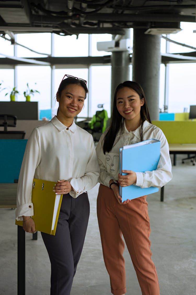 Women In White Long Sleeve Shirts Holding Binders