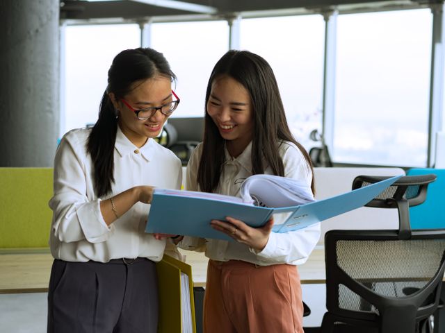 Two people reviewing a shared document on a laptop by a window