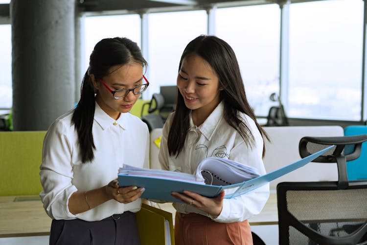 Two Women Reading A Document In The Office