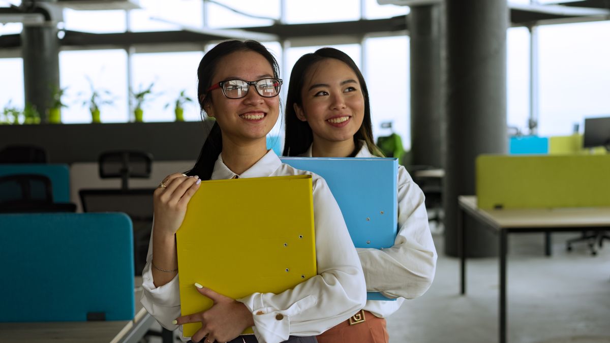 Two young professional women smiling in a stylish modern office.