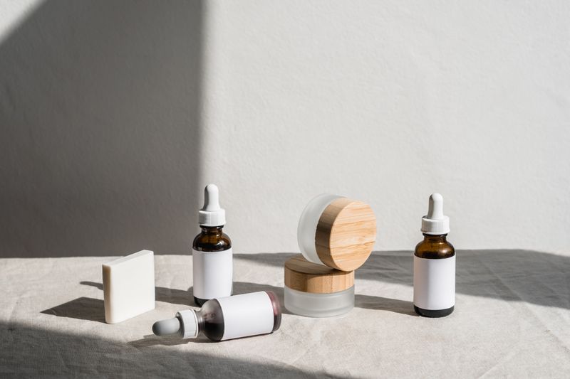 Flat lay of skincare products in jars and dropper bottles under soft natural light.