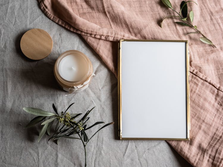 Empty Photo Frame Beside A Candle In A Glass Jar