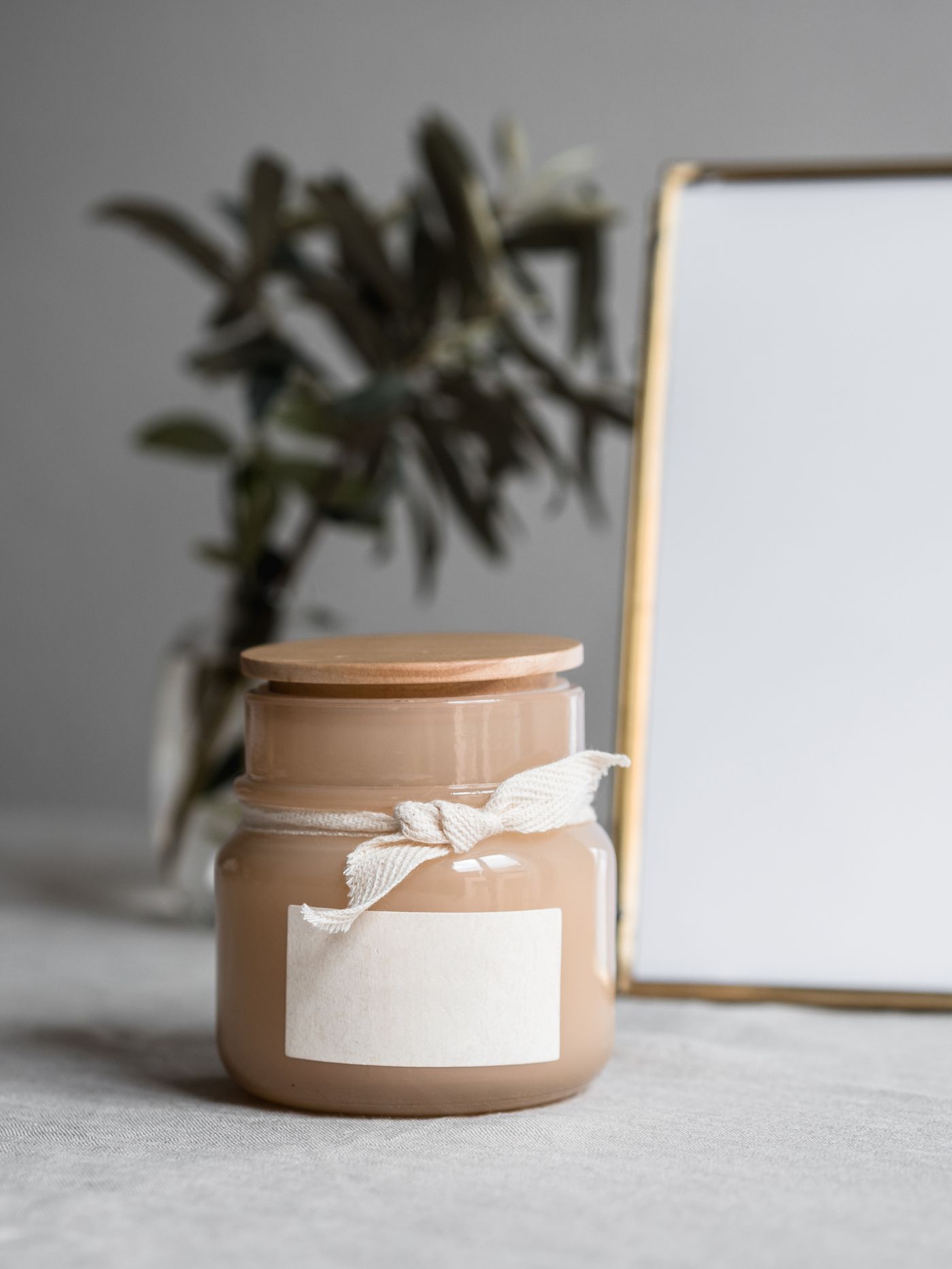 An unlit beige jar candle with a wooden lid and an unbranded paper label.