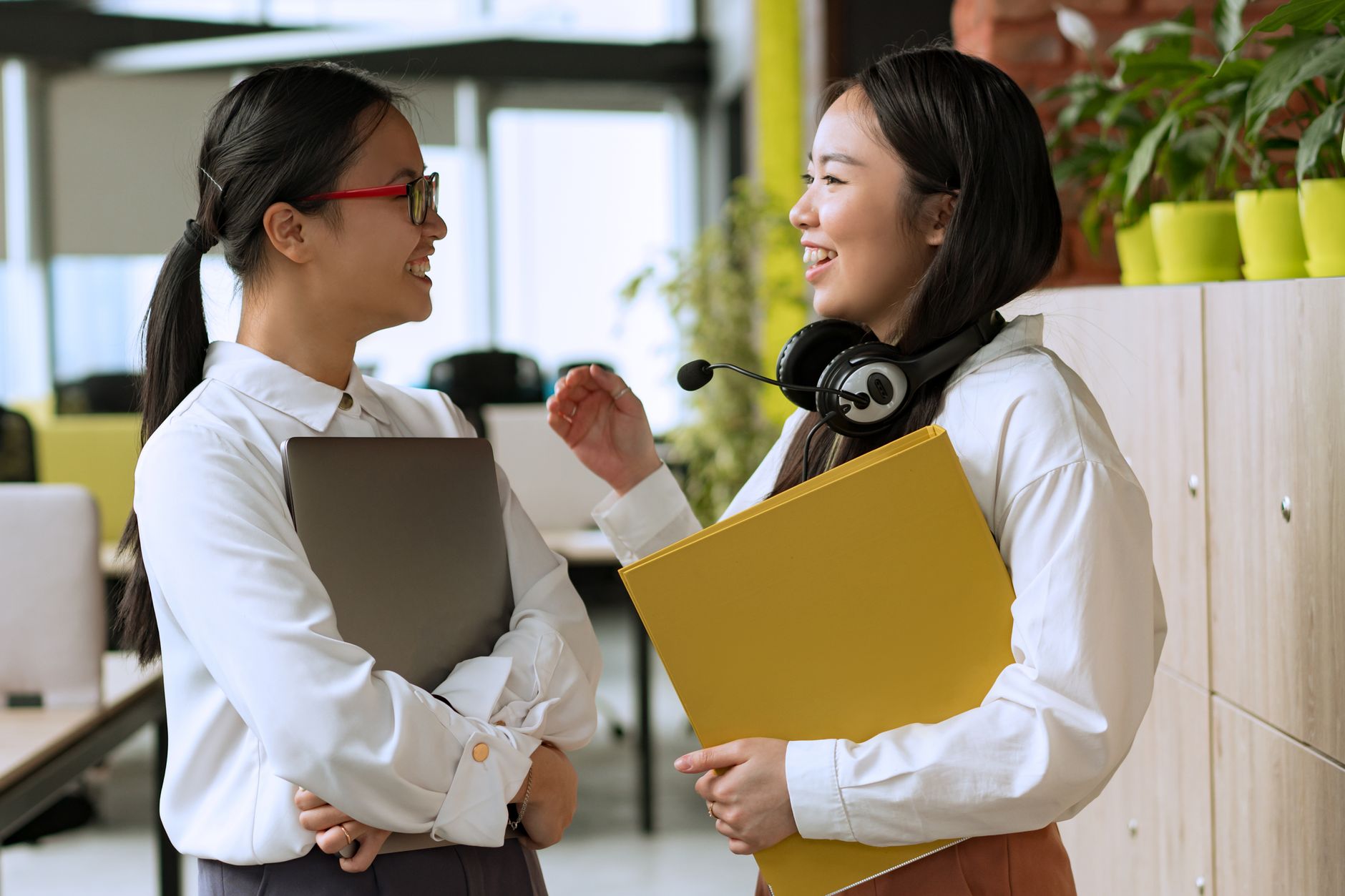 Two women colleagues conversing in a modern office, fostering teamwork.