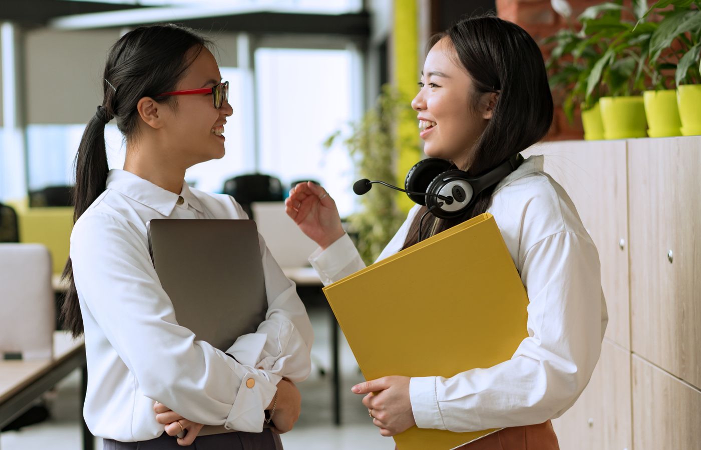 Two women colleagues conversing in a modern office, fostering teamwork.
