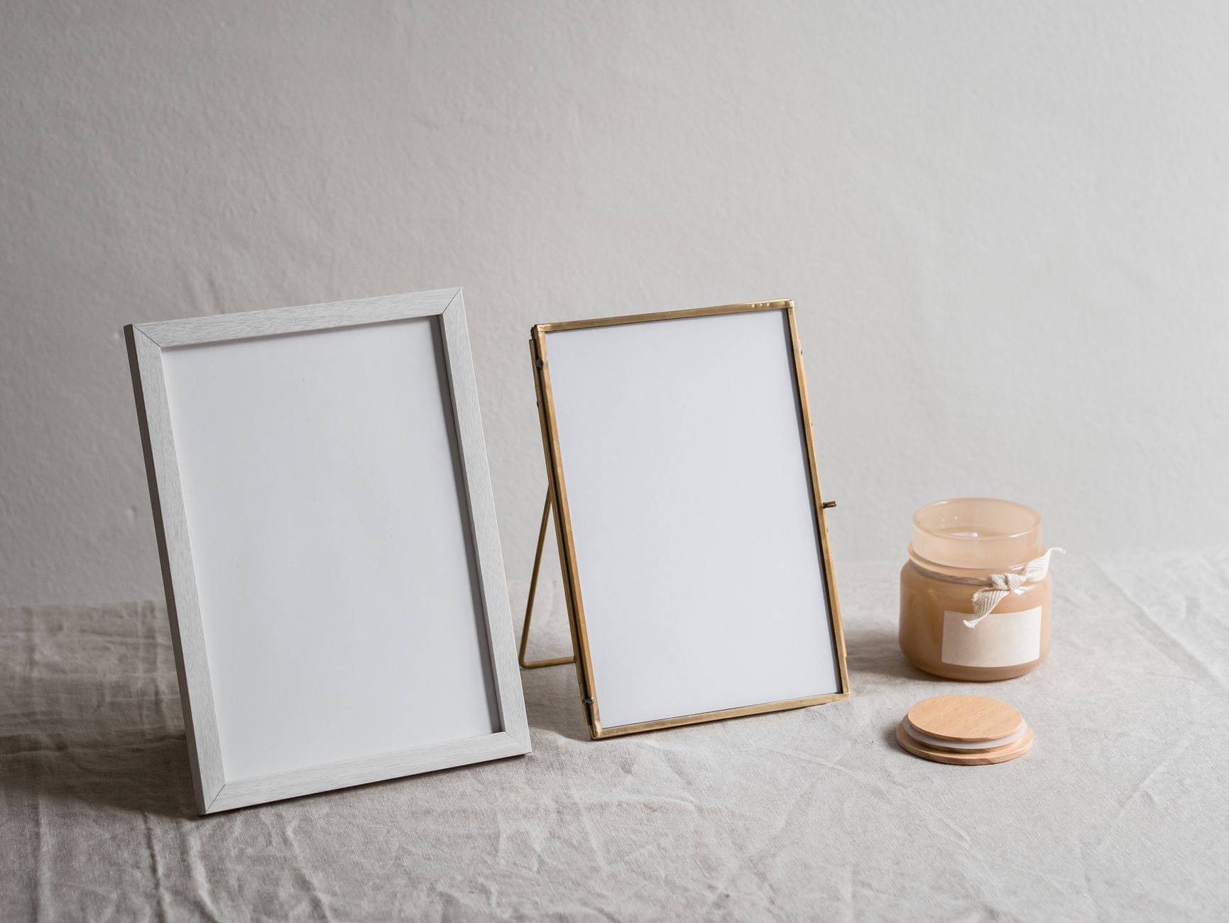 Minimalist composition featuring two empty photo frames and a decorative candle.