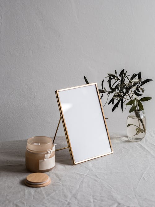 Free Empty Photo Frame Between a Glass vase with Plant and Jar with Candle Stock Photo