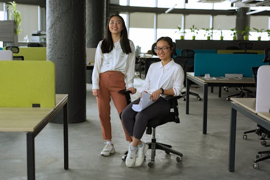 Two Asian women in a contemporary office, showcasing teamwork and innovation.