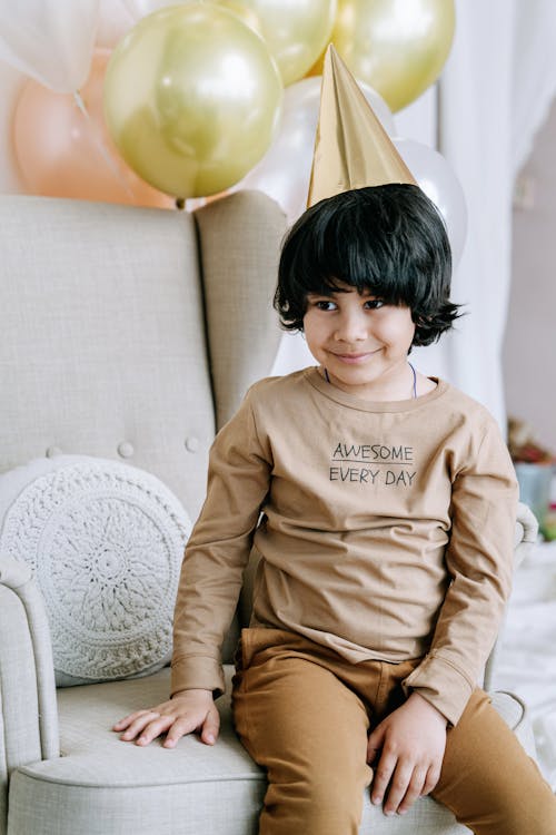 Boy Wearing Party Hat Sitting on Sofa Chair