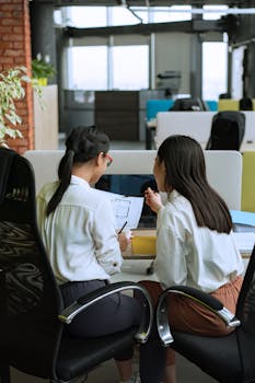 Two women working together on a project in a modern office environment.