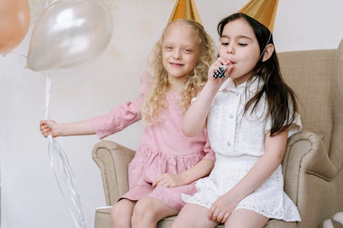 Free Girls Wearing Party Hat Sitting on Sofa Chair Stock Photo