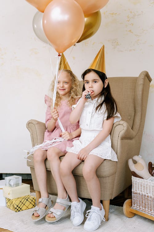 Children Sitting on Sofa Chair Wearing Party Hats