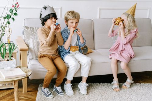 Free Three children in playful costumes sitting indoors, engaging in imaginative play with toys. Stock Photo