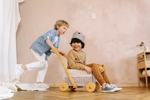 Free Boy Pushing a Cart with Another Boy Sitting on Wicker Basket Stock Photo