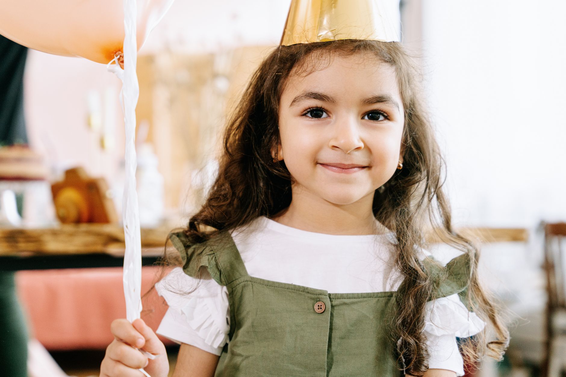luxury kids birthday Sheikh Zayed — Adorable girl in a party hat holding a balloon at a festive celebration.