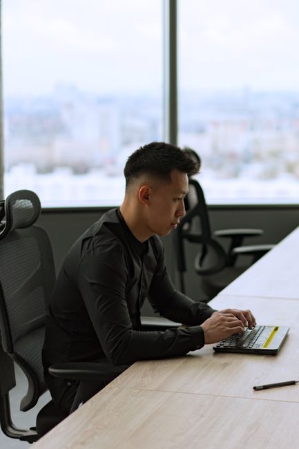 Asian businessman intently working on his laptop in a sleek, modern office space. Asian businessman intently working on his laptop in a sleek, modern office space.