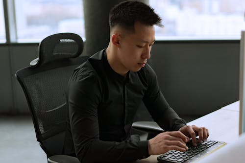 Free Man in Black Long Sleeve Shirt Using a Computer Keyboard Stock Photo