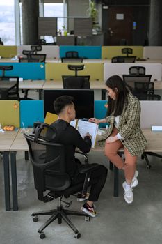 Two colleagues collaborate in a stylish open-plan office setting.
