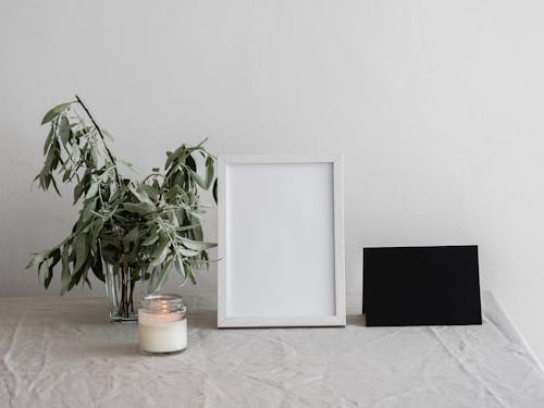 A Lit Candle Beside a White Picture Frame