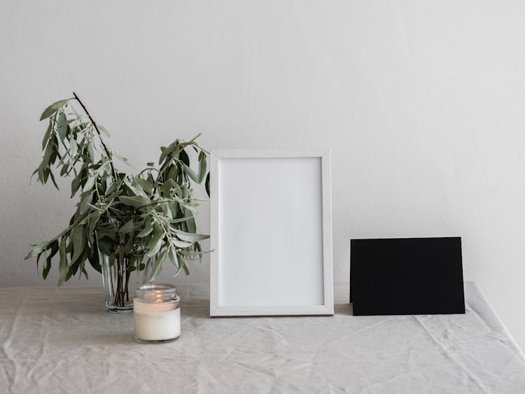 A Lit Candle Beside A White Picture Frame