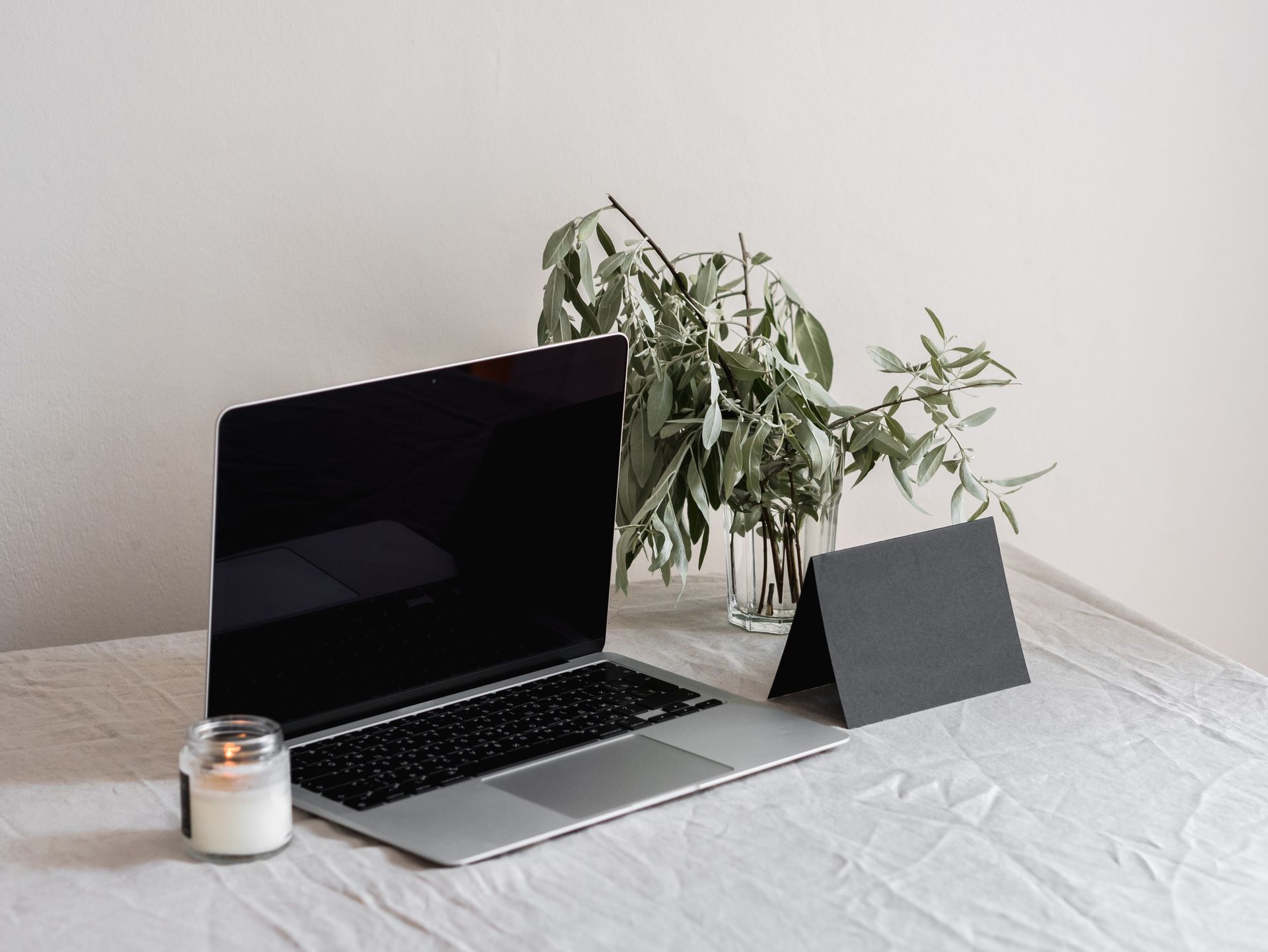 A modern workspace featuring a laptop, candle, and plant, evoking simplicity and focus.