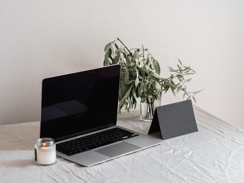 Free A modern workspace featuring a laptop, candle, and plant, evoking simplicity and focus. Stock Photo