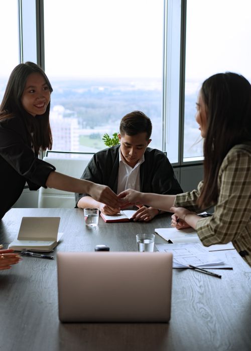 Free Team members collaborate in a bright office space with a view, using laptops and notes. Stock Photo