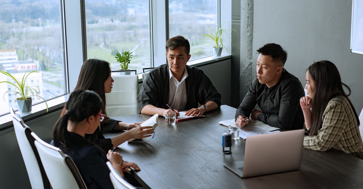 Group of Asian professionals having a meeting in a modern office setting.