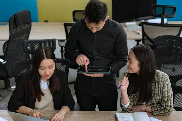 Group Of Young People Having A Conversation In An Office And Man Using A Tablet 