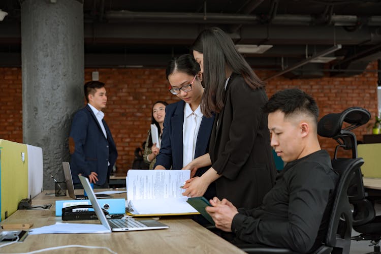 Women Standing While Looking At The Documents