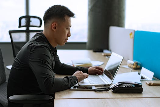 Business professional man working on laptop in a modern office setting.
