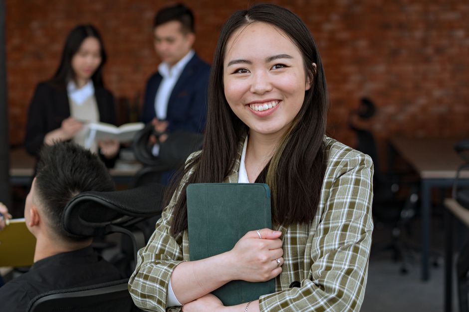 Photo by Mikhail Nilov Smiling woman in a professional office environment holding a tablet, conveying confidence and professionalism.