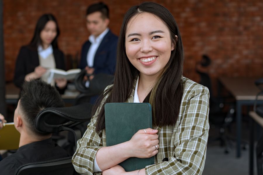 A smiling Filipina professional holding a tablet in a modern office