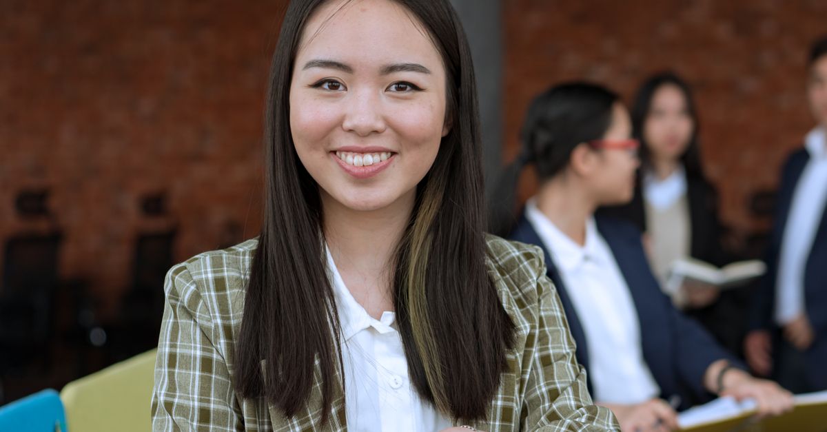 Smiling Asian woman in office, showcasing a professional work environment.