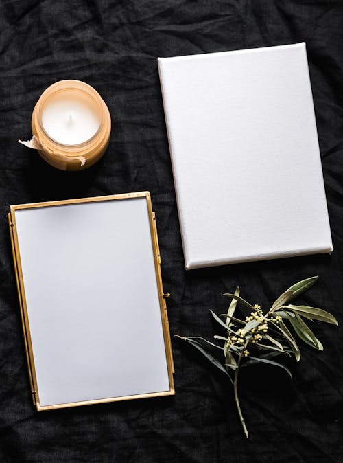 Blank Photo Frame Beside A Candle And Paper On Black Textile