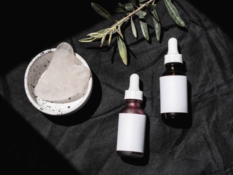 Elegant skincare product setup with gua sha tool and essential oils on a black background.