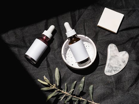 Chic arrangement of skincare bottles, gua sha tool, and bar soap on dark fabric.