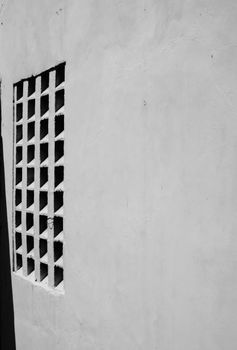 Black and white minimalist photo of a stucco wall featuring a geometric window design.
