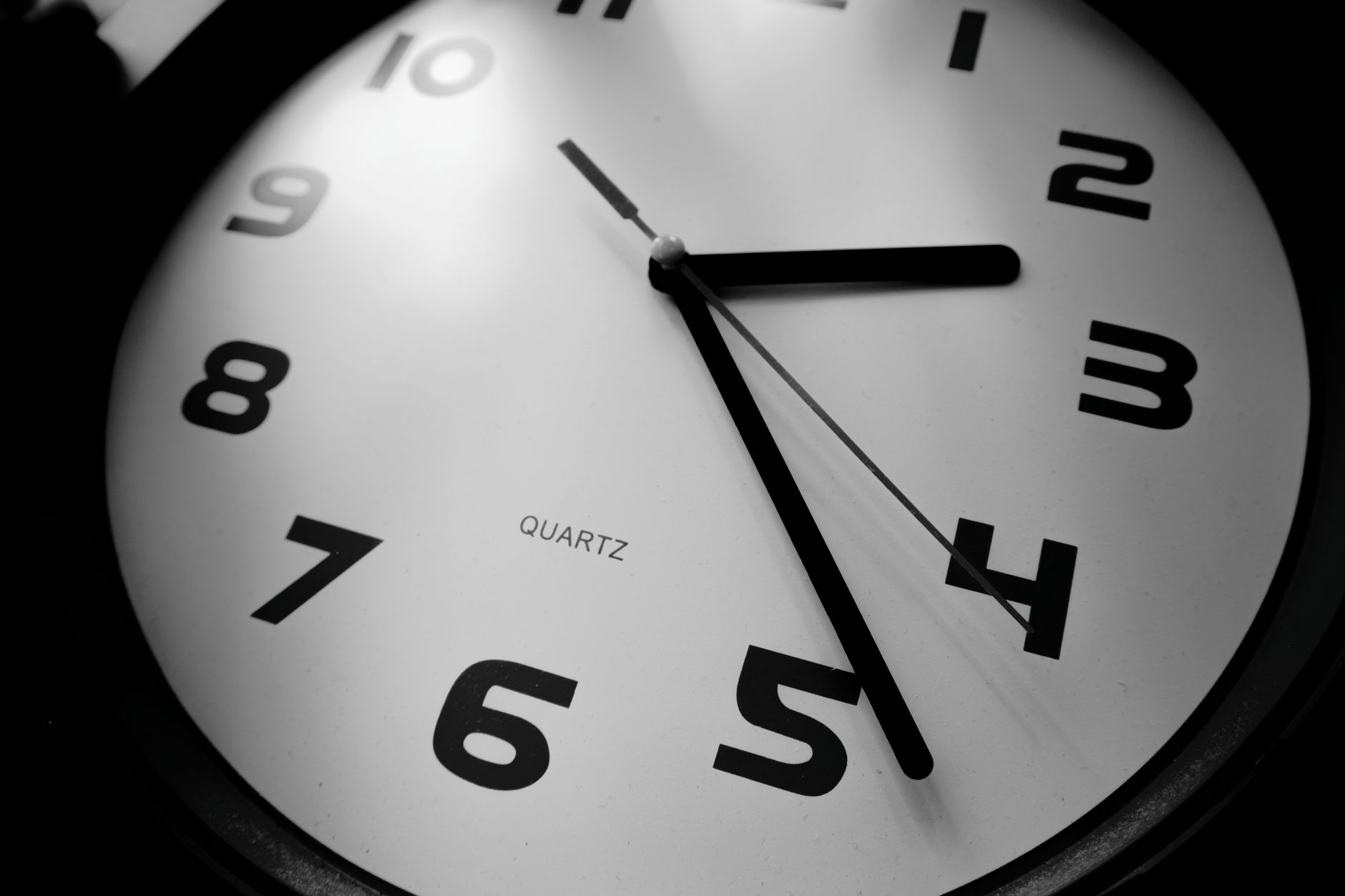 A detailed black and white close-up of a quartz clock emphasizing the numbers and time precision.
