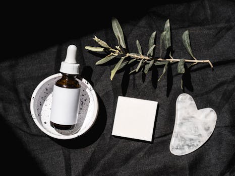 Elegant beauty product arrangement featuring a serum dropper bottle and gua sha on a black background.