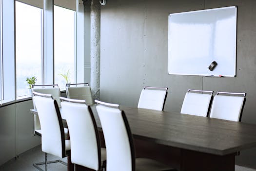 Spacious conference room featuring a modern whiteboard, sleek chairs, and large windows for natural light.