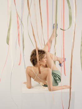 Elegant woman posing in a creative studio setup with colorful ribbons.