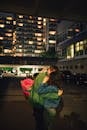 Woman in Blue Denim Jacket Sitting on Sidewalk during Night Time