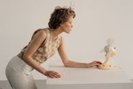 Woman in Floral Top Looking at an Electric Fan