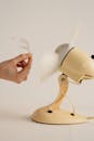 Close Up Photo of a Person Holding Feather in Front of an Electric Fan
