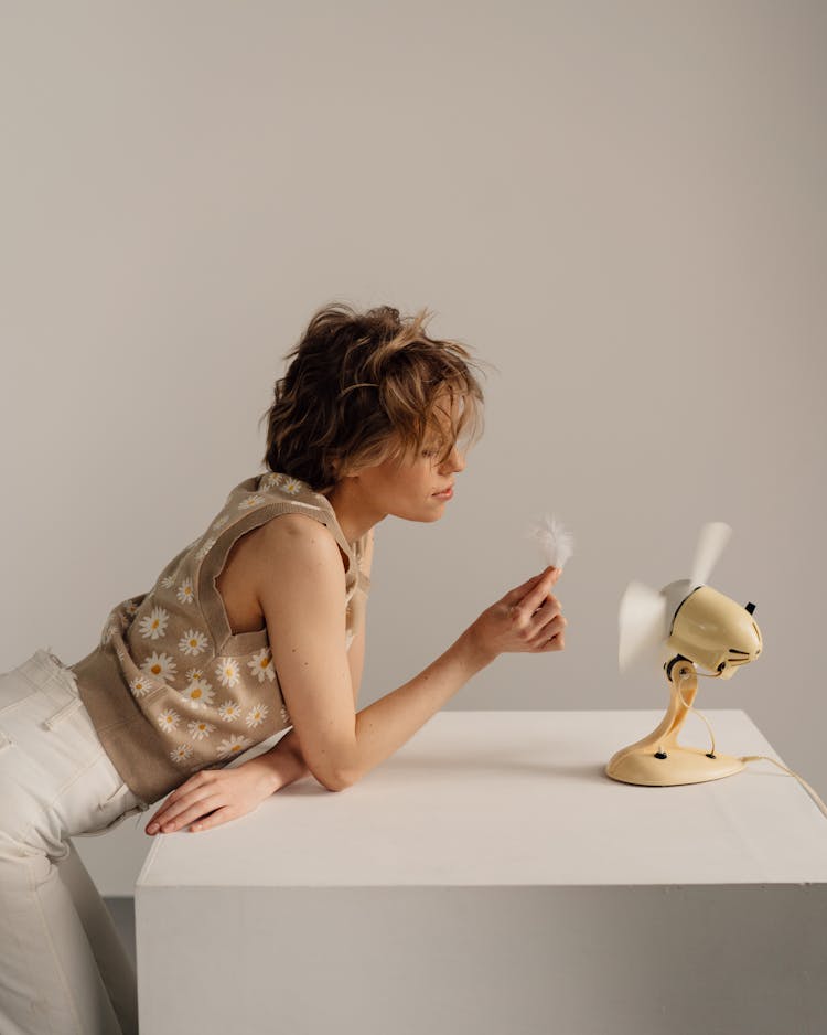 Woman In Front Of Electric Fan Holding A Feather