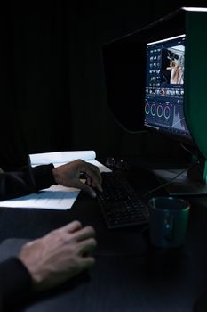 Close-up of a video editor working on color grading in a dimly lit room.