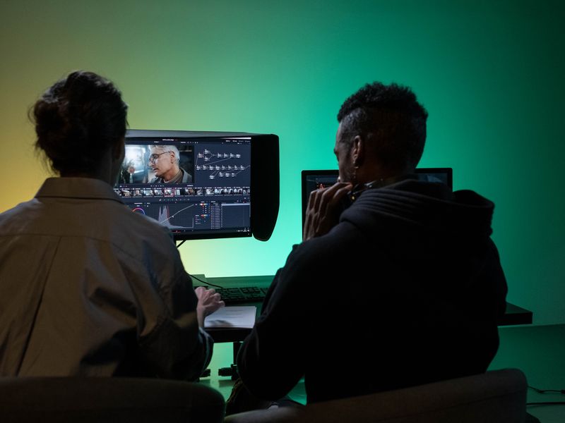 Two creatives colour grading video footage on an editing workstation